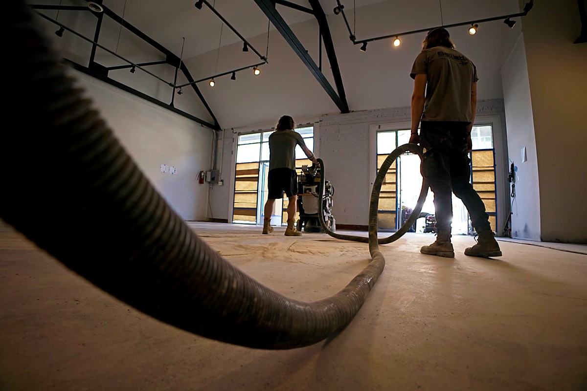 Flooring contractor mechanically grinding a concrete floor with dust collection equipment